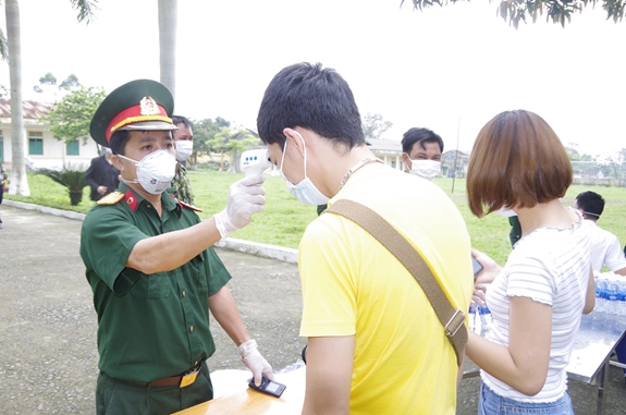 Thượng úy QNCN Nguyễn Quang Tiến kiểm tra thân nhiệt công dân trong khu cách ly tập trung.